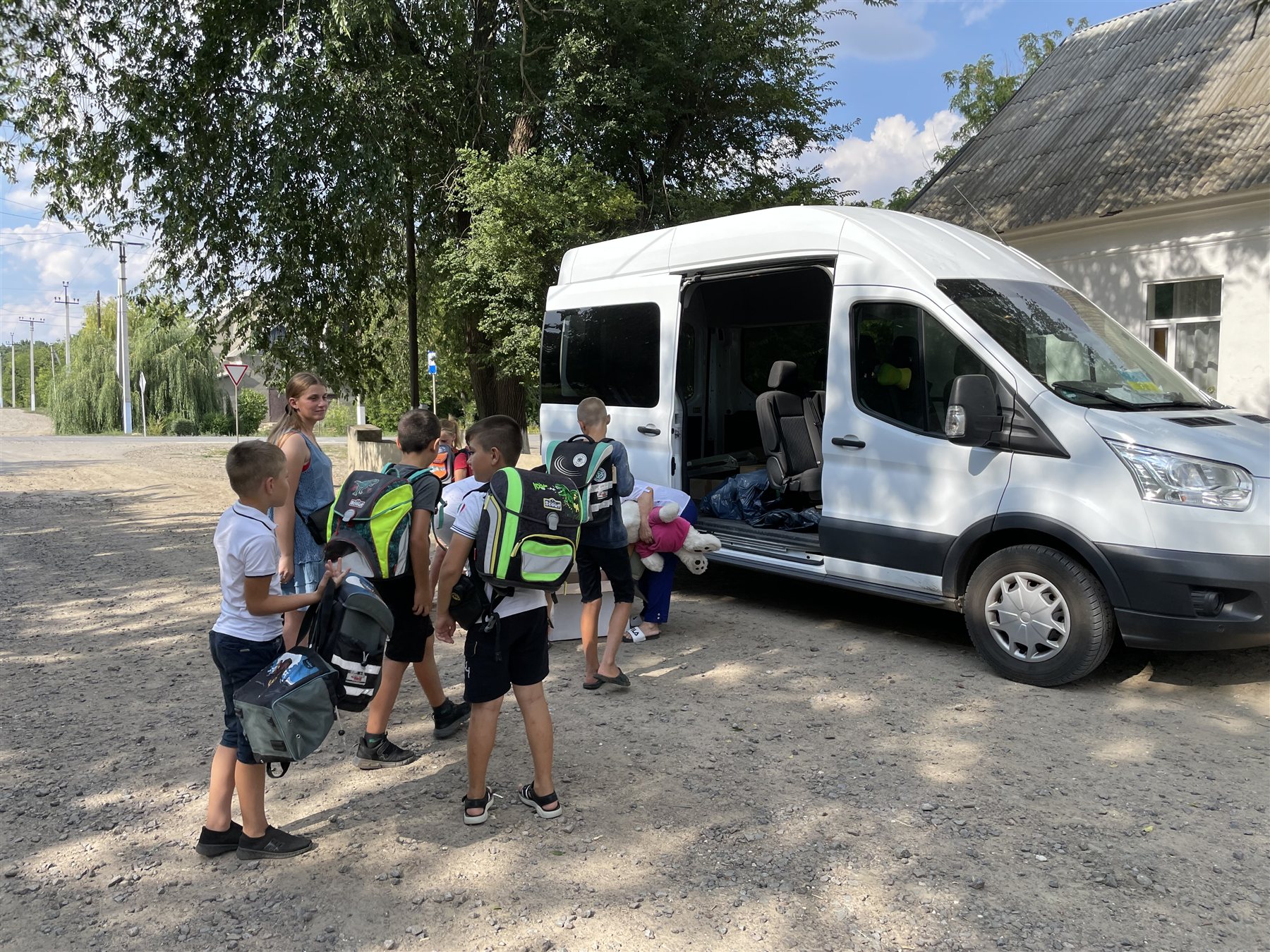 Schülerinnen und Schüler mit Schulranzen am Transportfahrzeug